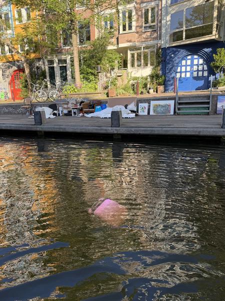 A vibrant canal scene unfolds at Zwanenburgwal, Centrum, Amsterdam, where historic canal houses with colorful facades line the water